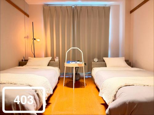 a room with two beds and a sign that says at ura 東横のヨコ in Okayama