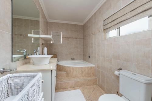 a bathroom with a tub and a sink and a toilet at Seaview Manor Exquisite Bed & Breakfast in Durban