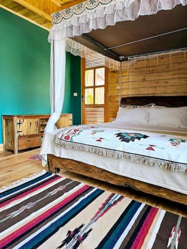 a bedroom with a canopy bed and a rug at Hidden Cabin in Iringa