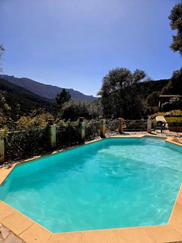 a large blue swimming pool with mountains in the background at Small chalet in Serriera
