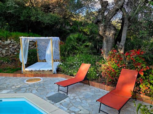 two red chairs and a bed next to a pool at Small chalet in Serriera