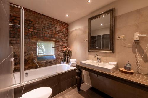 a bathroom with a tub and a sink and a toilet at Hotel Schinvelder Hoeve in Schinveld