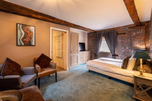 a bedroom with a bed and chairs and a brick wall at Hotel Schinvelder Hoeve in Schinveld