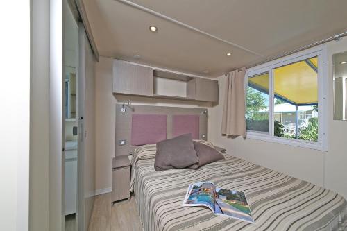 a bedroom with a bed with a magazine on it at San Francesco Camping Village in Desenzano del Garda