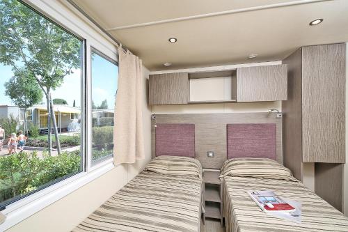 a room with two beds and a window at San Francesco Camping Village in Desenzano del Garda