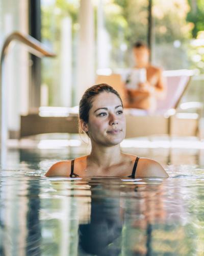 a woman is swimming in a swimming pool at Wellnesshotel Linde in Sulzberg