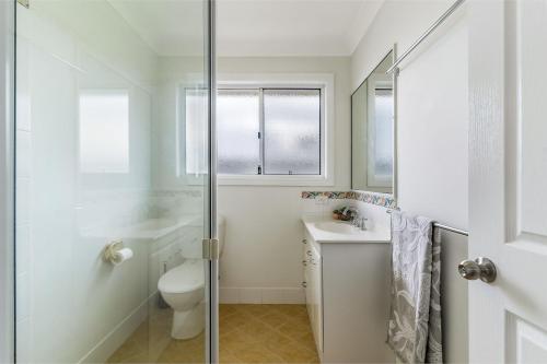 a white bathroom with a toilet and a sink at 1-41 Park Street in Evans Head