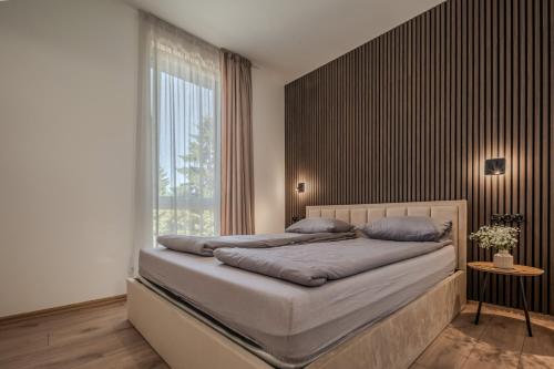 a bedroom with a bed with a large window at TOPOLIŲ Apartamentai in Palanga
