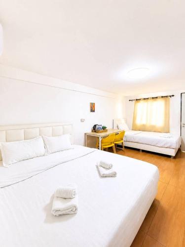 a white bedroom with a large bed and a couch at Magic Garden Residence Bangkok in Bangkok