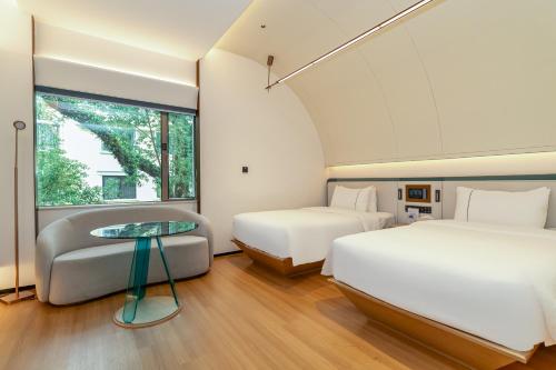 a bedroom with two beds and a table and a couch at Yee Hotel Shamian Guangzhou in Guangzhou