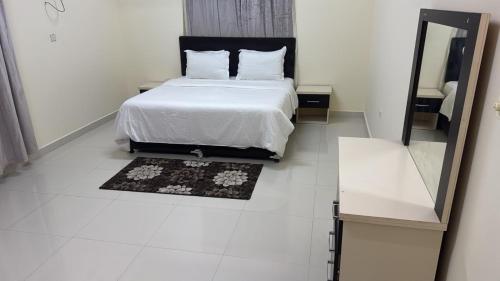 a white bedroom with a bed and a mirror at هدى صلالة in Salalah