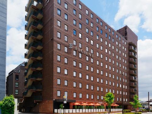 a tall brick building with balconies on it at Hotel Elcient Kyoto Hachijoguchi in Kyoto