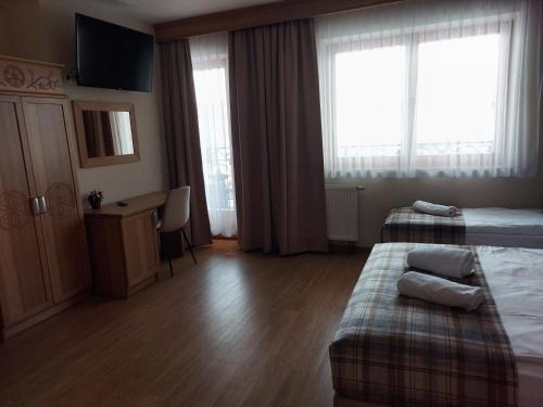 a hotel room with a bed and a desk and window at Dom Wypoczynkowy U Chramca in Białka Tatrzańska