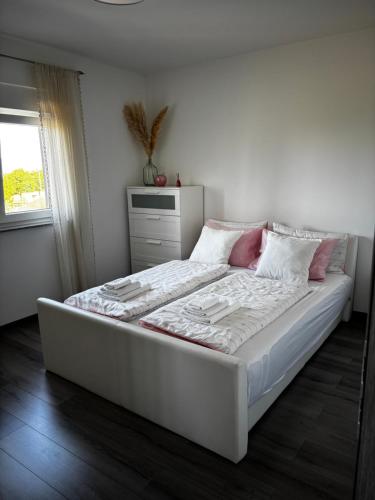 a bedroom with a large white bed with pink pillows at Mila in Vodnjan