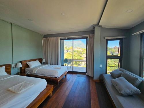 a bedroom with two beds and a couch and windows at Piney Stay ไพนี่สเตย์ เขาค้อ in Campson