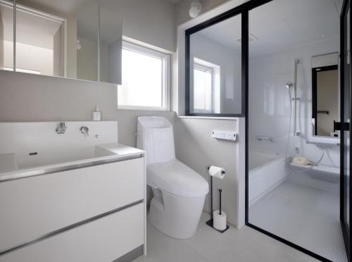 a white bathroom with a toilet and a sink at Adagio Retreat Tokachidake in Biei