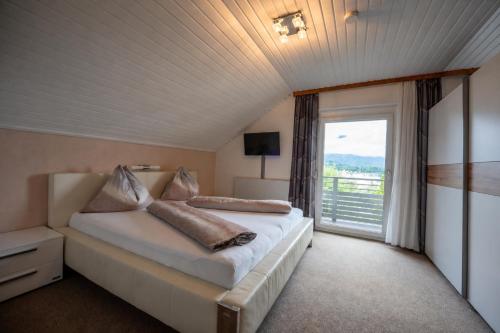 a bedroom with a bed and a large window at Gästehaus Wulz-Lesjak in Egg am Faaker See