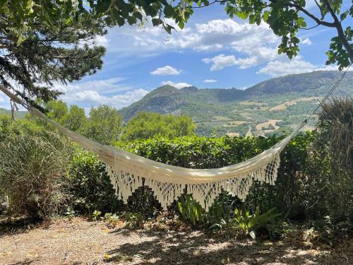 a hammock hanging from a tree with mountains in the background at La Traversière Condorcet in Condorcet