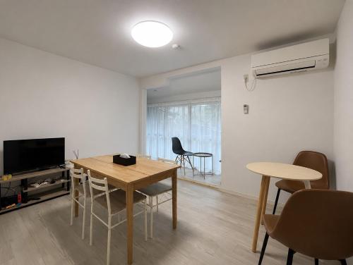 a living room with a table and chairs and a television at Guest House TETSU in Oshima