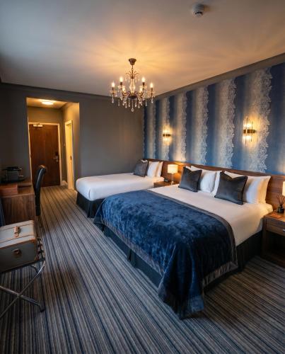 a hotel room with two beds and a chandelier at Kilian's Lodge Hotel in Mullagh