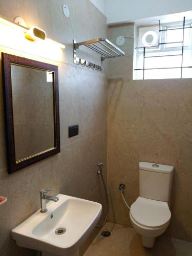 a bathroom with a sink and a toilet and a mirror at Orange Elite Stays Whitefield in Bangalore