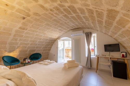 une chambre avec un grand lit et un mur en pierre dans l'établissement Endea Suite Rooms & Lounge SPA, à Matera