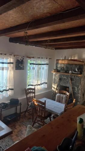 a living room with a table and a stone fireplace at Vikend kuća Zlatarski DAR in Nova Varoš