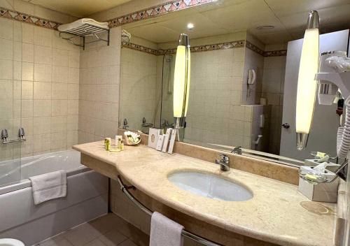 a bathroom with a sink and a tub and a mirror at Lancaster Tamar Hotel- Hadath in Beirut