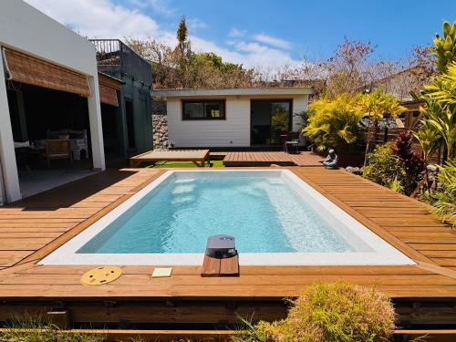 a swimming pool on a wooden deck with a house at Villa Parenthèse - Piscine & Bungalow - 8 Pers in Trois Bassins