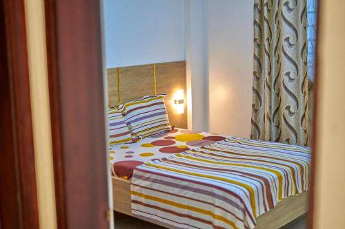 a bedroom with a bed with a striped blanket at RÉSIDENCE Chloé in Bonamoussadi