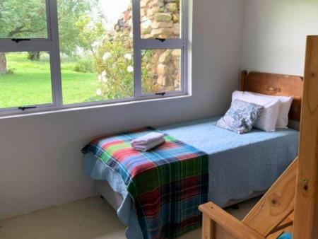 a bed sitting in a room with a window at The Boathouse in Harrismith