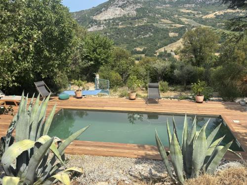 a swimming pool with two chairs in a yard at La Traversière Condorcet in Condorcet