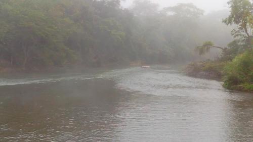 a misty river with a boat in the middle at Don Santiago Guesthouse Downtown in San Ignacio