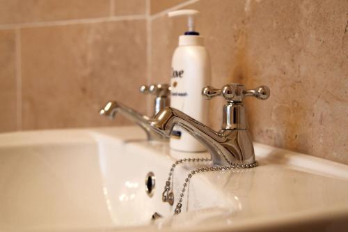 a bathroom sink with a faucet and a bottle of soap at The Windmill Inn - Whitby in Whitby