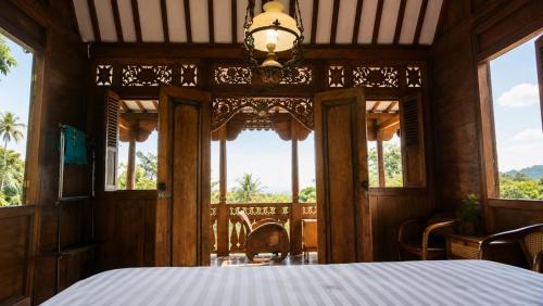 a bedroom with a bed and some windows at Mahatva Borobudur Resort in Borobudur