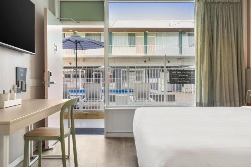 a hotel room with a bed and a desk and a window at Nightcap at the Cavenagh in Darwin
