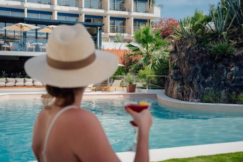 a woman in a hat sitting next to a swimming pool at Radisson Hotel Cannes Seaside in Cannes