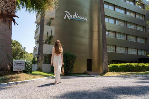 a woman walking down a street in front of a building at Radisson Hotel Cannes Seaside in Cannes