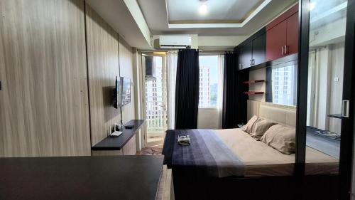 a bedroom with a bed and a television in it at Malioboro City Apartement by Dev's Room in Seturan