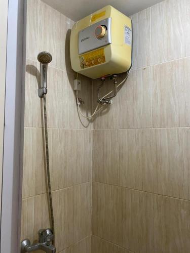 a shower in a bathroom with a dispenser on the wall at Malioboro City Apartement by Dev's Room in Seturan