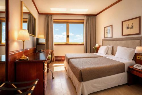 a hotel room with two beds and a desk at Ferretti Hotel Catullo Verona in San Martino Buon Albergo
