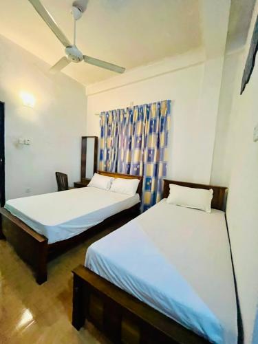 a bedroom with two beds and a ceiling fan at Aluvihare Residence in Matale