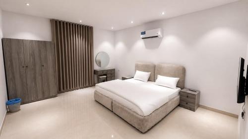 a white bedroom with a bed and a mirror at أرياف سويت in Al Baha