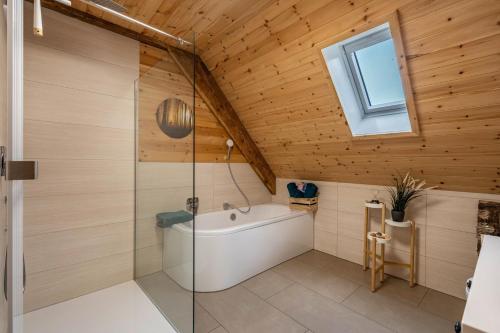 a bathroom with a tub and a glass shower at Schwarzwald Chalet - Karlshütte in Neuweg
