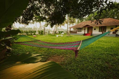 a hammock in a yard in front of a house at Alleppey Backwater Resort in Alleppey