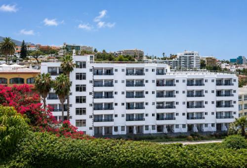 a white building with flowers in front of a city at Muthu La Perla Tenerife in Puerto de la Cruz