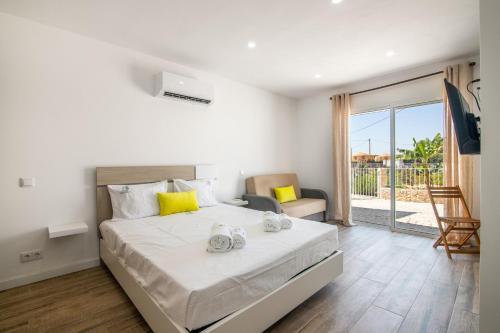 a bedroom with a large white bed with yellow pillows at Vilas Salero in Moncarapacho