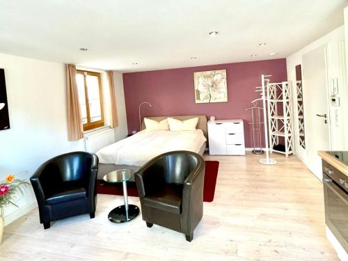 a bedroom with a bed and two black chairs at Apartment am Schloss in Sigmaringen