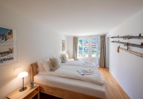 a white bedroom with a bed and a window at Chalet Mittaghorn Apt 7 in Wengen