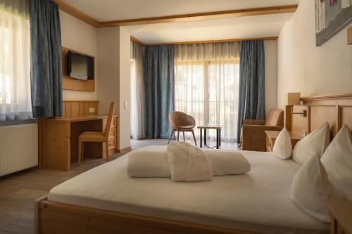 ein Hotelzimmer mit einem großen Bett und einem Schreibtisch in der Unterkunft Hotel & Residence Rose in Sterzing